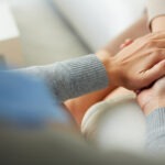 Two people gently holding hands